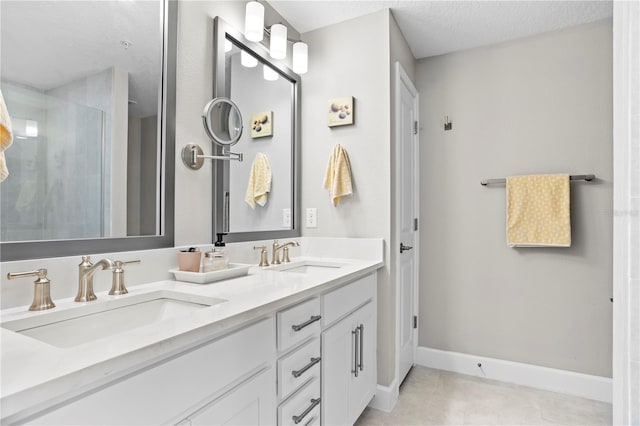 full bath with baseboards, a tile shower, a sink, and tile patterned floors