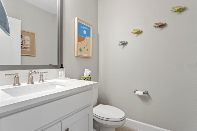 bathroom featuring toilet, baseboards, and vanity