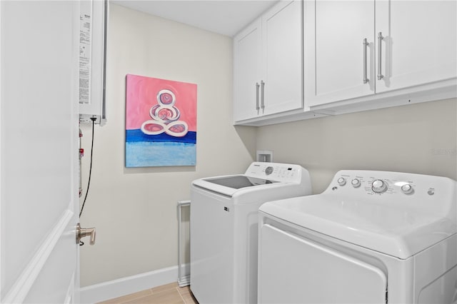 clothes washing area featuring washer and dryer, cabinet space, and baseboards