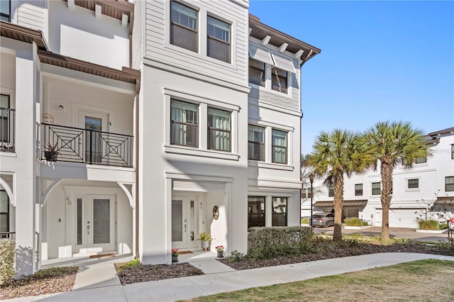 exterior space featuring a balcony, stucco siding, and french doors