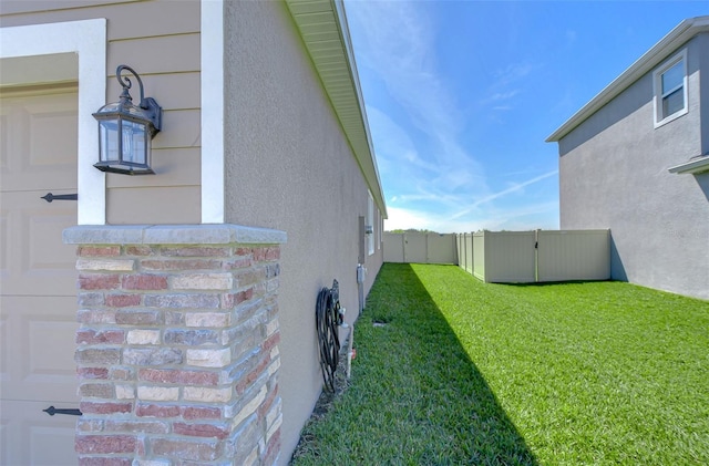 view of side of home featuring a garage, a yard, fence, and stucco siding