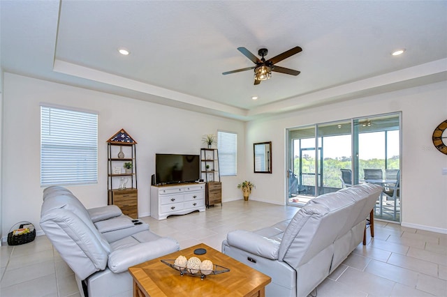 living room with light tile patterned floors, baseboards, a raised ceiling, and recessed lighting