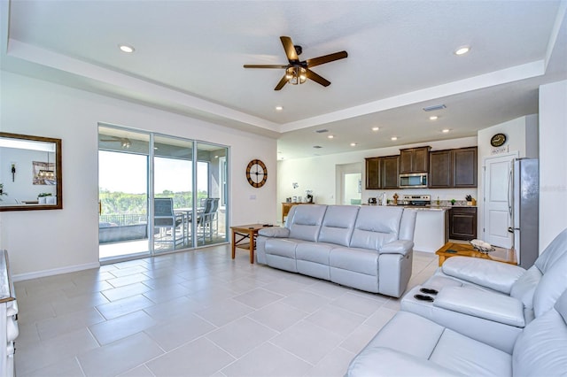 living area featuring light tile patterned floors, recessed lighting, a raised ceiling, and baseboards