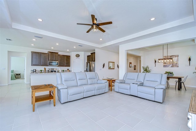 living room featuring light tile patterned flooring, a raised ceiling, visible vents, and recessed lighting