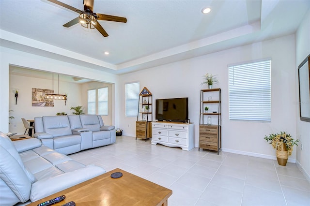 living room with light tile patterned floors, a tray ceiling, recessed lighting, and baseboards