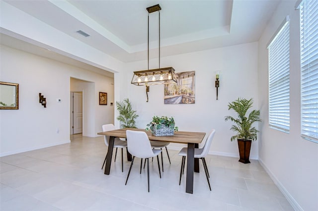 dining area featuring a raised ceiling and baseboards