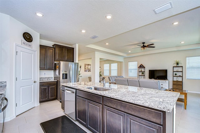 kitchen featuring stainless steel appliances, visible vents, open floor plan, a kitchen island with sink, and a sink