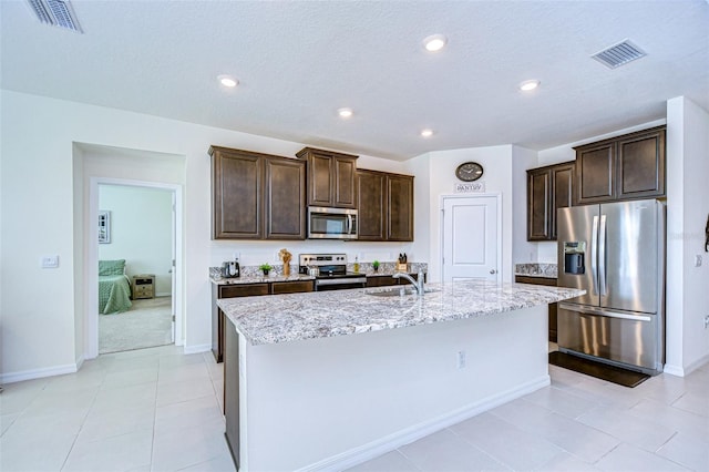 kitchen with visible vents, appliances with stainless steel finishes, a sink, and a kitchen island with sink