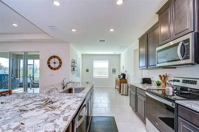 kitchen with visible vents, light stone counters, appliances with stainless steel finishes, dark brown cabinets, and a sink