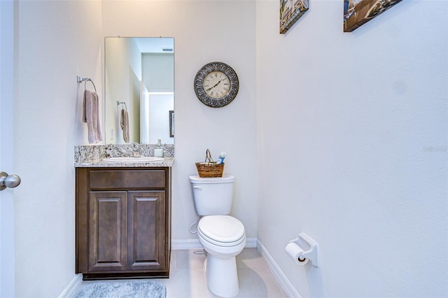 half bath with toilet, tile patterned flooring, vanity, and baseboards