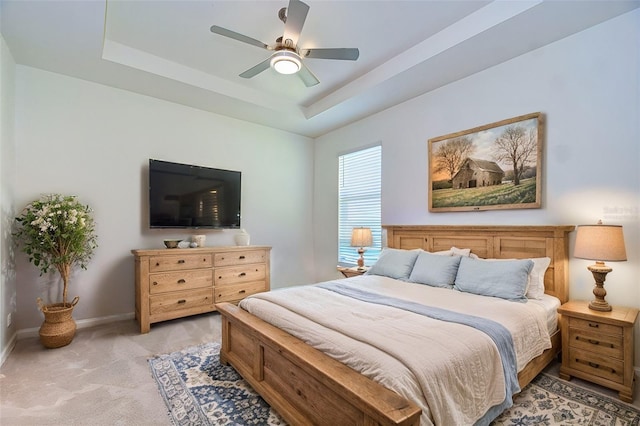 bedroom featuring light carpet, ceiling fan, a raised ceiling, and baseboards