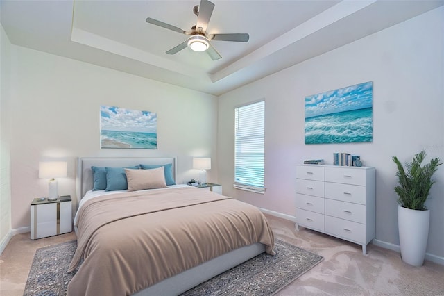 bedroom with light carpet, ceiling fan, baseboards, and a raised ceiling