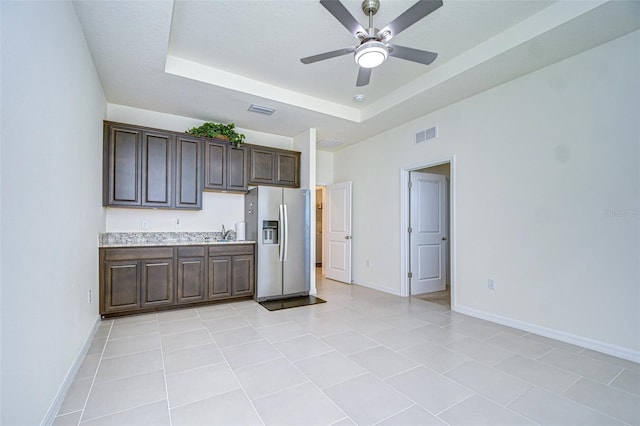 kitchen with dark brown cabinetry, visible vents, light countertops, stainless steel fridge with ice dispenser, and a raised ceiling