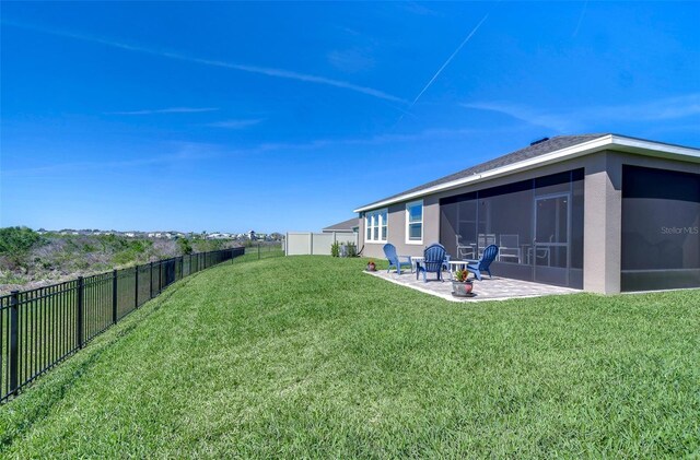 view of yard featuring a sunroom, a fenced backyard, and a patio