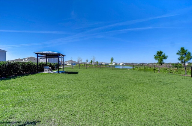 view of yard with a gazebo, a water view, and fence