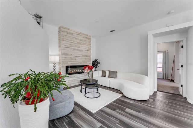 living room with visible vents, wood finished floors, and a high end fireplace