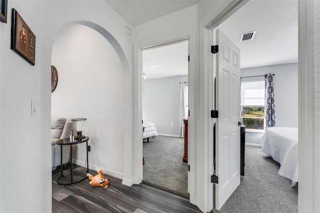 14247 Spanish Wells Dr, Hudson, FL 34667 - corridor featuring arched walkways, visible vents, baseboards, and dark colored carpet