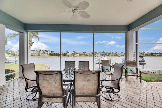 sunroom / solarium featuring a water view, plenty of natural light, and a ceiling fan