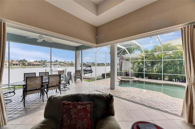 sunroom featuring ceiling fan and a water view