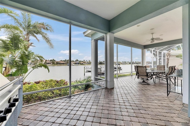 sunroom / solarium with a water view and a ceiling fan