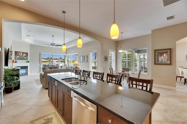 kitchen with a center island with sink, visible vents, open floor plan, a sink, and dishwasher