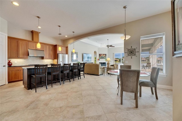 kitchen featuring arched walkways, open floor plan, decorative light fixtures, under cabinet range hood, and high end fridge