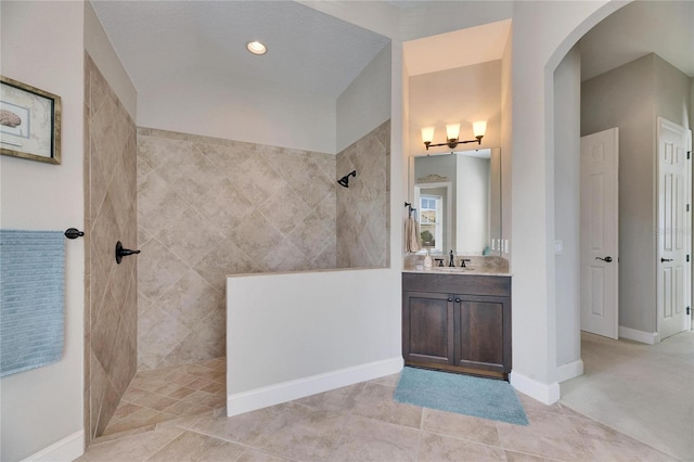 bathroom featuring tile patterned flooring, walk in shower, vanity, and baseboards