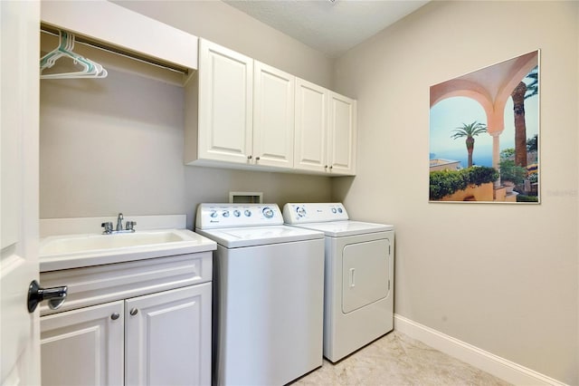 washroom featuring washing machine and dryer, cabinet space, a sink, and baseboards