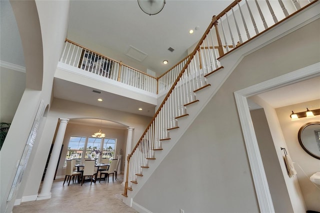 stairway featuring a towering ceiling, ornate columns, baseboards, and arched walkways