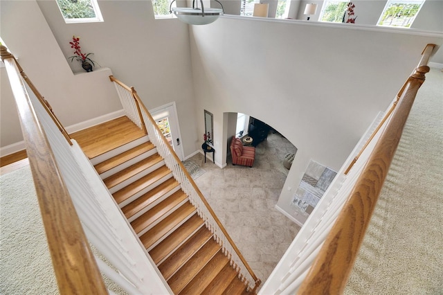 staircase with arched walkways, a wealth of natural light, and baseboards