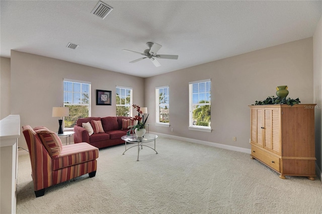 living room featuring light carpet, ceiling fan, visible vents, and baseboards