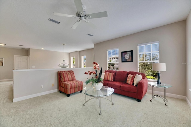 living area with baseboards, visible vents, and light colored carpet