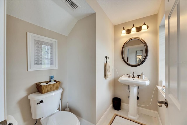 bathroom featuring toilet, visible vents, baseboards, vaulted ceiling, and tile patterned floors