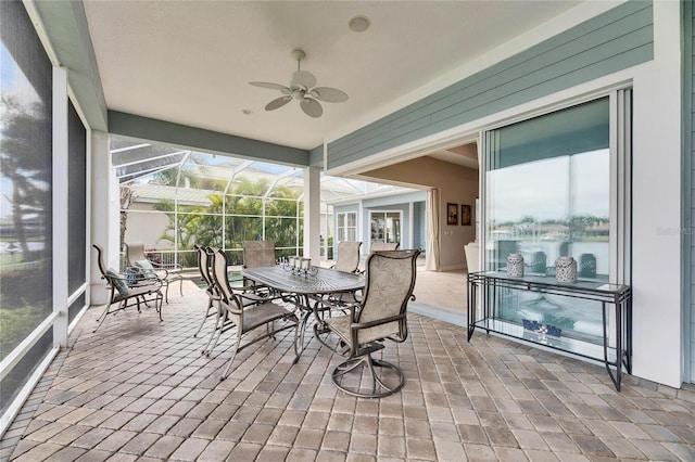 sunroom / solarium with a ceiling fan and a water view