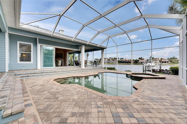 view of pool featuring a water view, glass enclosure, a pool with connected hot tub, and a patio area