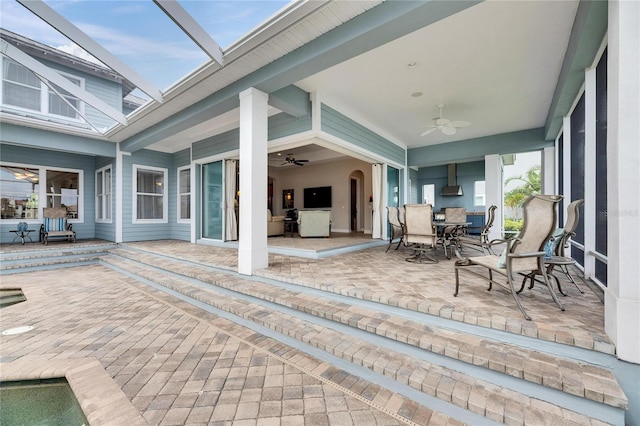 view of patio featuring ceiling fan, glass enclosure, and outdoor dining space