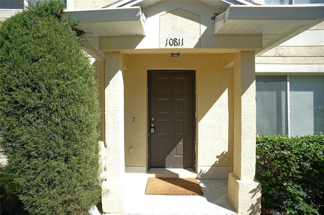 doorway to property featuring stucco siding