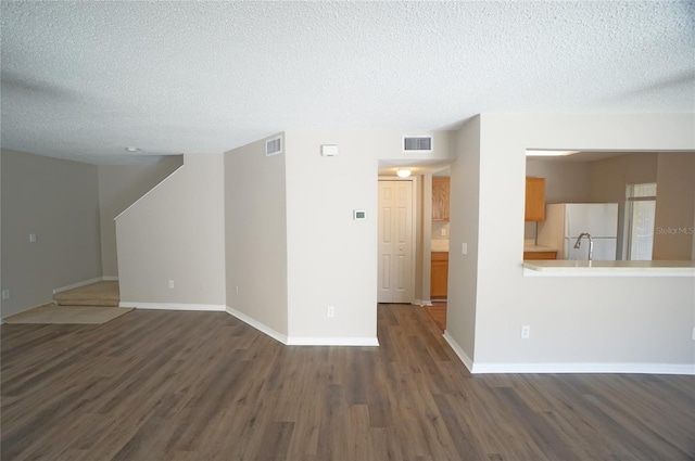 unfurnished room featuring visible vents, dark wood finished floors, a textured ceiling, and baseboards