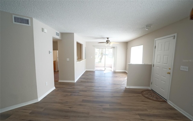 spare room with dark wood-type flooring, visible vents, and a textured ceiling