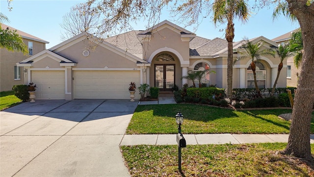 view of front facade featuring driveway, an attached garage, stucco siding, a front lawn, and french doors