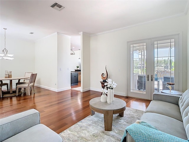 living room with visible vents, a notable chandelier, wood finished floors, and crown molding