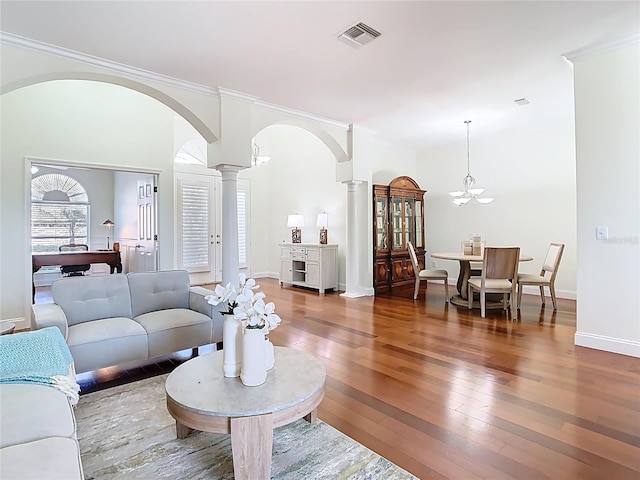 living room featuring visible vents, ornate columns, arched walkways, hardwood / wood-style flooring, and crown molding