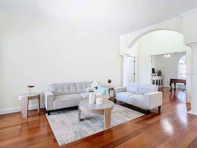 living room featuring decorative columns, arched walkways, wood finished floors, and ornamental molding