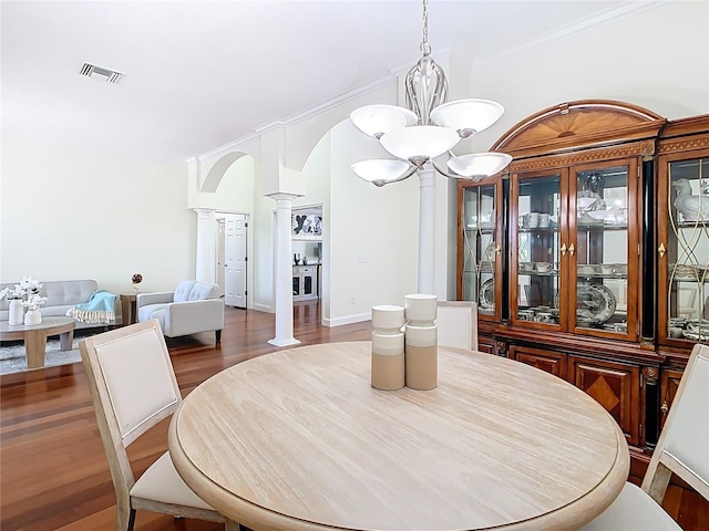 dining space with dark wood-style flooring, an inviting chandelier, visible vents, and ornate columns