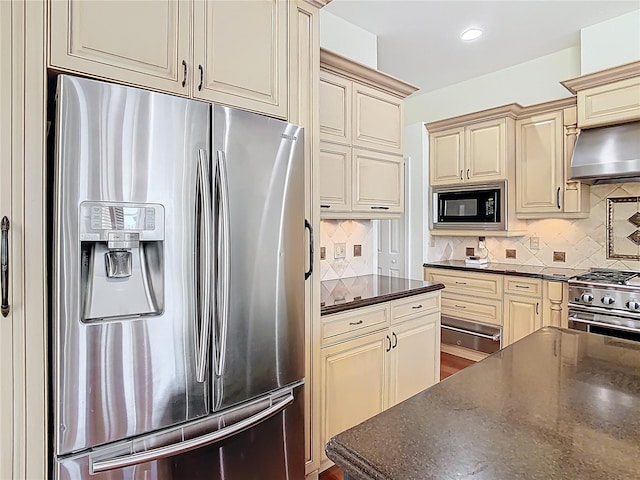 kitchen with cream cabinetry, backsplash, appliances with stainless steel finishes, and range hood