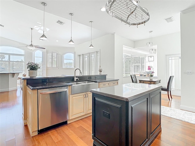 kitchen featuring visible vents, an island with sink, a sink, light wood-style floors, and dishwasher