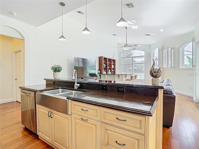 kitchen featuring stainless steel dishwasher, dark countertops, cream cabinets, and visible vents