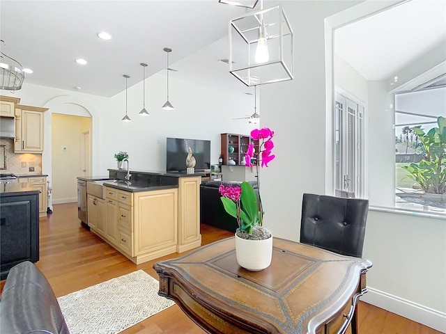 dining space with arched walkways, recessed lighting, baseboards, and light wood-style floors