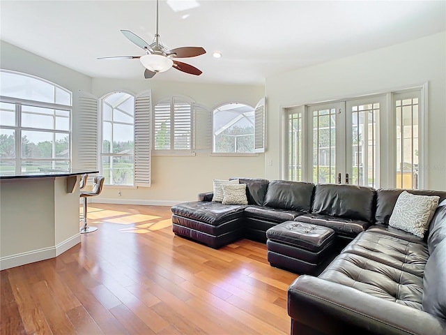 living area featuring baseboards, light wood-type flooring, recessed lighting, french doors, and a ceiling fan