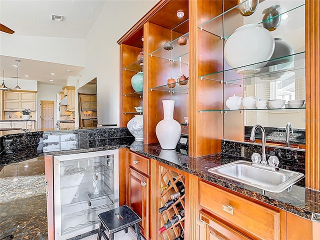 kitchen with dark stone countertops, wine cooler, visible vents, and a sink